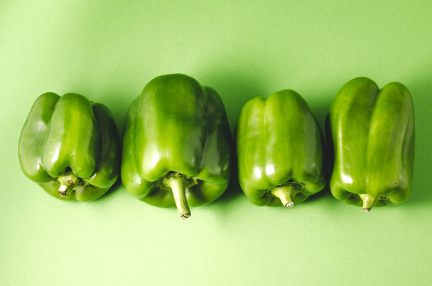 row green paprika pepper close-up/row green paprika pepper over green background, top view - Foto, Imagen
