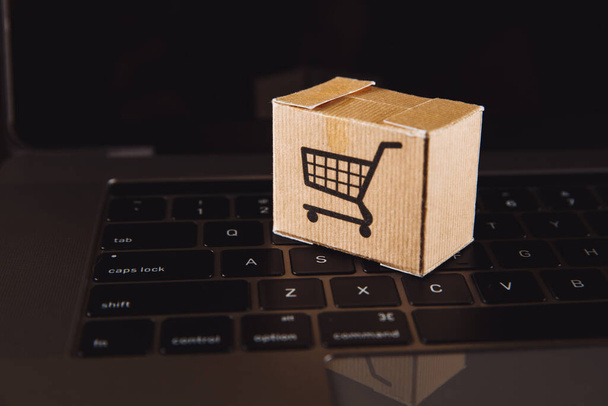 Boxen in einem Trolley auf einer Laptop-Tastatur. Ideen zum Online-Shopping: Online-Shopping ist eine Form des elektronischen Handels, die es Verbrauchern ermöglicht, Waren direkt von einem Verkäufer über das Internet zu kaufen. - Foto, Bild