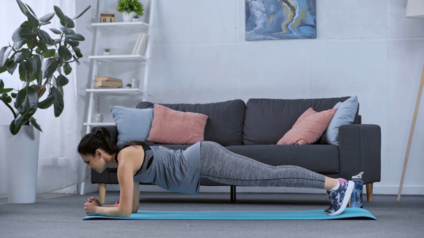 Vue latérale de la sportive debout dans la planche sur tapis de fitness à la maison
  - Séquence, vidéo