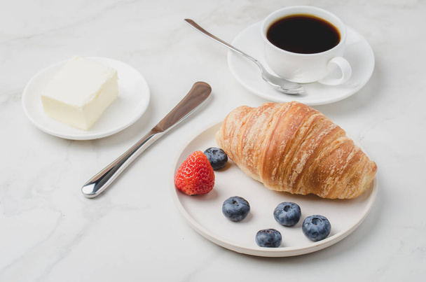 Delicious breakfast with fresh coffee, fresh croissants and berries. Selective focu - Фото, изображение