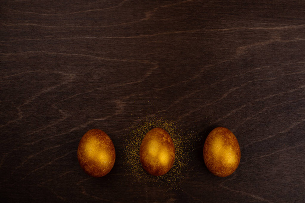 Three big golden easter eggs on dark wooden background copy space for text - Foto, Imagem
