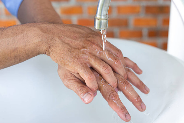 El joven se lava las manos en un fregadero desinfectando el virus de la colona para el saneamiento y reduciendo la propagación de COVID-19 extendiéndose por todo el mundo, concepto de Higiene, Saneamiento
. - Foto, imagen