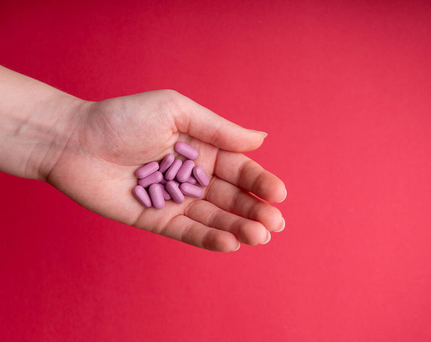 Mano de mujeres sosteniendo pastillas rosas. Primer plano de una joven con una pastilla rosa en una mano. pastillas medicinales. pastillas de vitaminas. medicamentos para el estómago, la erección, el sueño, digestivo, medicamentos
 - Foto, imagen