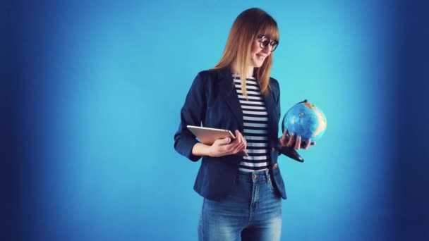 travel agent girl with tablet and globe on a blue background. - Filmmaterial, Video