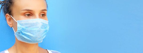 Woman in medical mask on a blue background. Concept for COVID-19, medical articles and news - Foto, Imagem