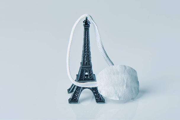 az Eiffel-torony miniatúrája, Franciaország ikonja, és arcmaszk törtfehér alapon - Fotó, kép