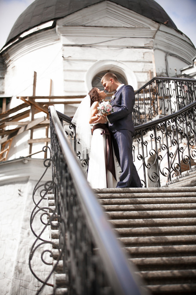Groom no terno confessando seu amor à noiva bonita na escada
 - Foto, Imagem