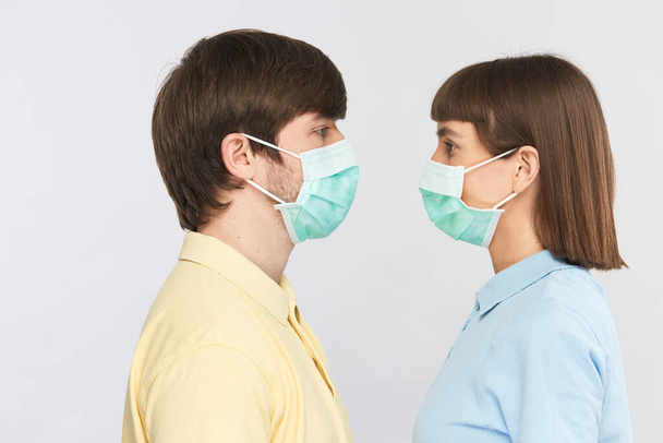 молодые люди в защитных масках, стоящих лицом к лицу, стерильный сезон во время пандемии коронавируса
 - Фото, изображение