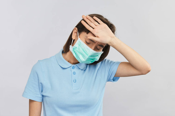 αδύναμη γυναίκα με ασθένεια έλεγχο της θερμοκρασίας του σώματος στο μέτωπο και να φορούν αποστειρωμένη μάσκα για την αποφυγή coronavirus - Φωτογραφία, εικόνα