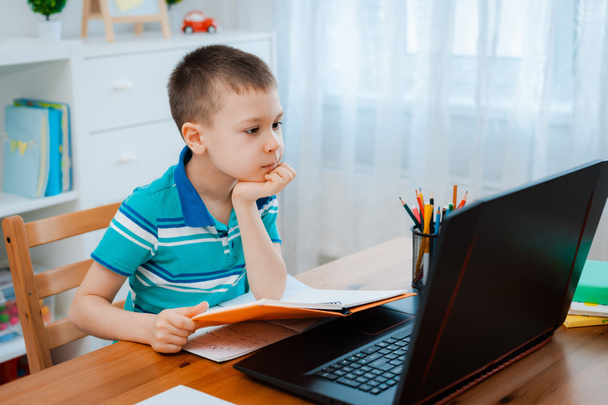 Дистанційне навчання онлайн-освіти. Хлопчик вчиться вдома і робить шкільне домашнє завдання. Навчання на домашній дистанції
. - Фото, зображення