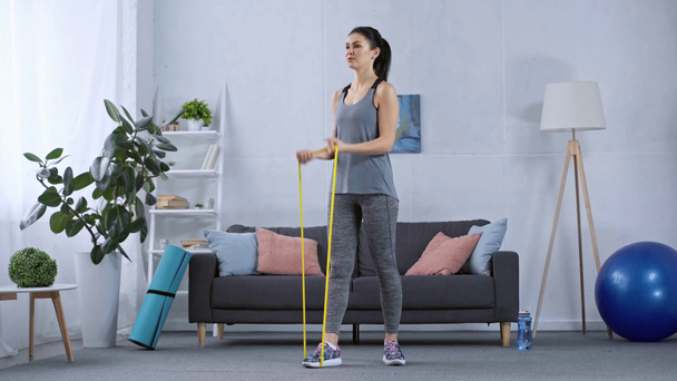 Sportswoman pulling up resistance band while training at home - Séquence, vidéo