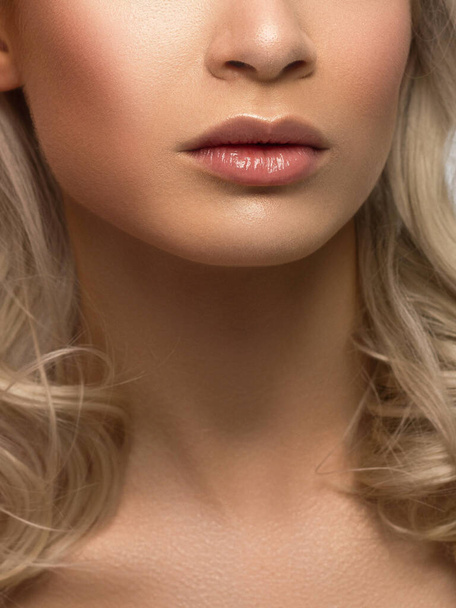 Sexy full lips. Natural gloss of lips and skin of the woman. The mouth is closed. Lip augmentation, cosmetology. Pink lips and a long neck. Delicate clean skin and wavy blond hair. Face powder - Фото, изображение