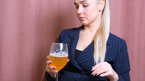 Female alcoholism for young blond woman holding bubbly wine, beer. Woman relaxing after work by drinking wine in the kitchen - Photo, Image
