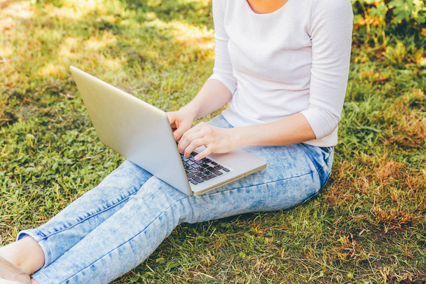 Szabadúszó üzleti koncepció. Nő lába, zöld a fű, gyep a városi park laptop pc számítógépen dolgozik. Életmód hiteles őszinte diák lány tanul a szabadban. Mobil iroda - Fotó, kép
