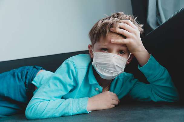 Больной ребенок с инфекцией или вирусом, мальчик в маске на карантине дома
 - Фото, изображение
