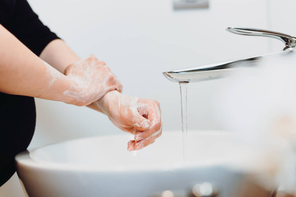 close up details of beautiful pregnant woman washing hands and cleaning hands from germs, bacteria and viruses with soap and water - Photo, image