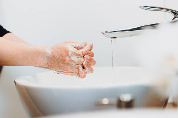 close up details of caucasian woman washing hands and cleaning hands from germs, bacteria and viruses with soap and water - Photo, image