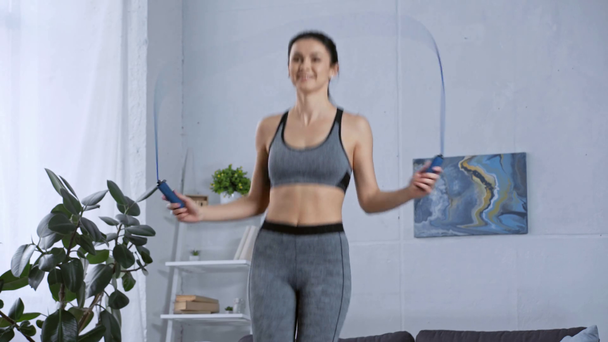 Χαμογελαστή αθλήτρια άσκηση με σχοινάκι στο σπίτι  - Πλάνα, βίντεο