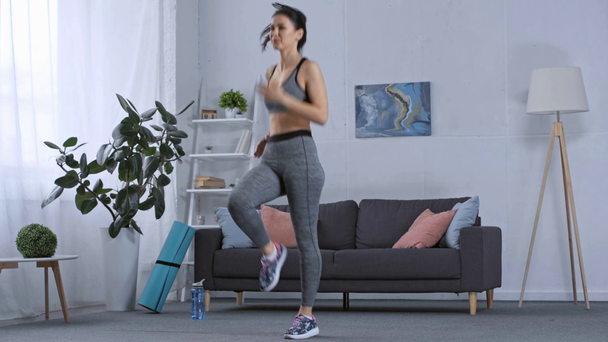 Sporcu kadın evde antrenman yaparken koşuyor. - Video, Çekim