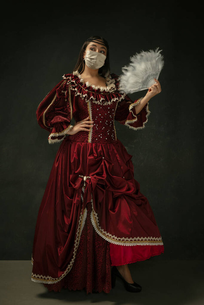 Medieval young woman as a duchess wearing protective mask against coronavirus spread - Фото, зображення