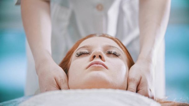 Masaż - masażystka ugniatająca brodę młodej kobiecie dłońmi - Zdjęcie, obraz