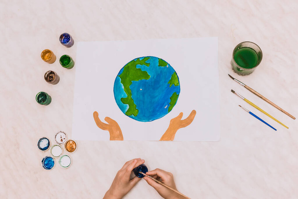 terra dia Terra azul verde bola redonda em forma de palmas pintadas mãos de uma criança. escovas, aquarela, criança desenha, gouache.geography planeta, globo desastre global
 - Foto, Imagem