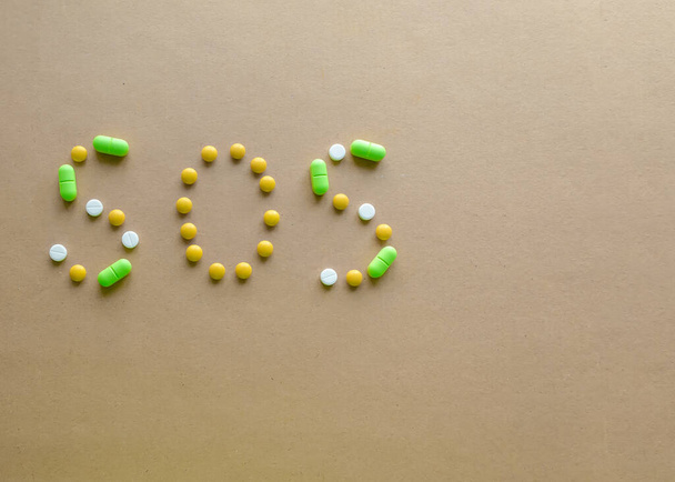 Inscriptie SOS van tabletten op een lichte achtergrond. Het begrip ziekte - Foto, afbeelding