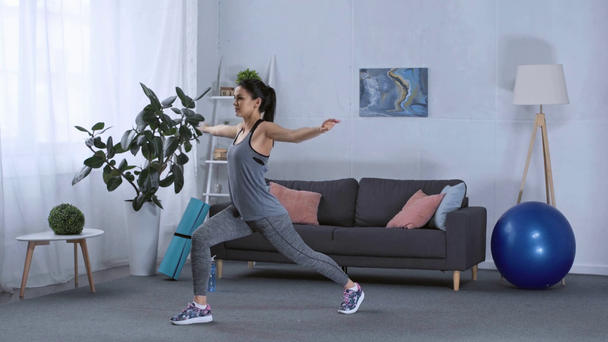 Вид збоку спортсменки робить лаунж під час тренування вдома
 - Кадри, відео