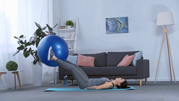Side view of sportswoman training with fitness ball at home - Imágenes, Vídeo