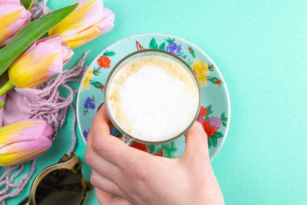 A mão da mulher leva café latte xícara em vidro transparente elegante com chantilly no fundo da hortelã
. - Foto, Imagem