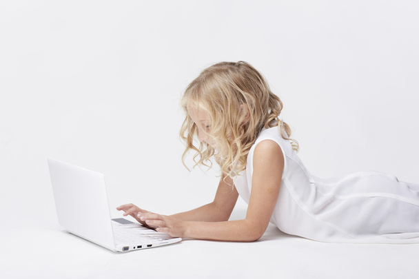 Beautiful blonde little girl with netbook, white background - Photo, Image