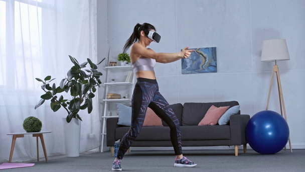 Sportswoman in vr headset playing video game in living room - Footage, Video
