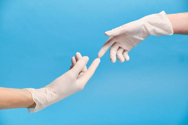 Twee gehandschoende handen raken elkaar tijdens de pandemische quarantaine. Quarantaineconcept.  - Foto, afbeelding