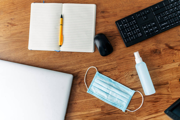 Mask and sanitizer on the desktop, near keyboard - Фото, изображение