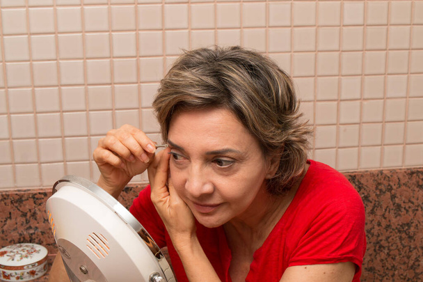 Жінка набиває брови парою з колодязів перед живим дзеркалом - Фото, зображення