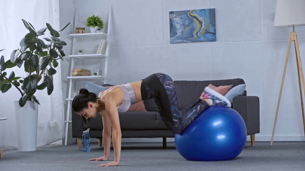 Vista lateral de la deportista haciendo ejercicio con la pelota de fitness en casa
  - Imágenes, Vídeo