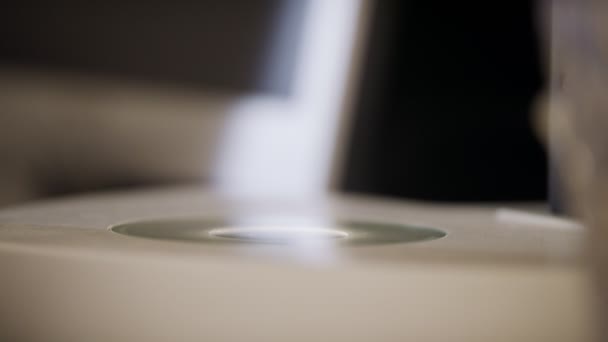 Close up on hand placing a petri dish under a microscope - Кадри, відео