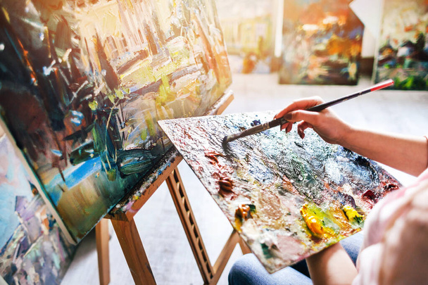 Girl artist paints an oil painting on canvas. Brush dips into the palette - Fotó, kép