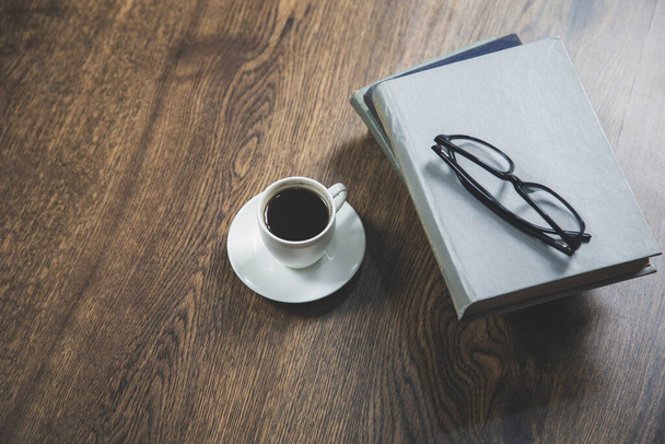 glasses on the books and coffee on desk - Фото, зображення