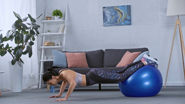 Vista lateral da esportista fazendo flexões com bola de fitness em casa
  - Filmagem, Vídeo