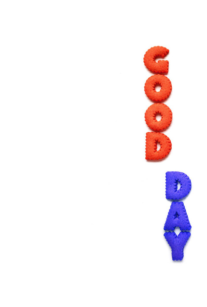 Imagen vertical de las palabras BUEN DÍA deletreado con galletas en forma de alfabeto rojo y azul sobre fondo blanco
 - Foto, imagen