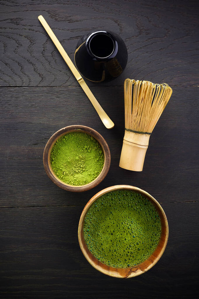 抹茶パウダー。有機抹茶茶道。健康的な飲み物だ。黒木の背景に伝統的な日本酒 - 写真・画像