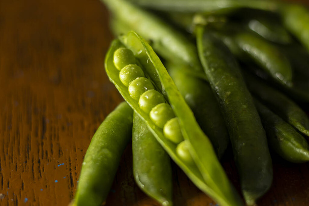 新鮮な緑のエンドウ豆とポッドは木製のテーブルに焦点を当て - 写真・画像