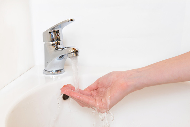 Close-up of human hands being washed under faucet in bathroom, isolated on white - Photo, Image