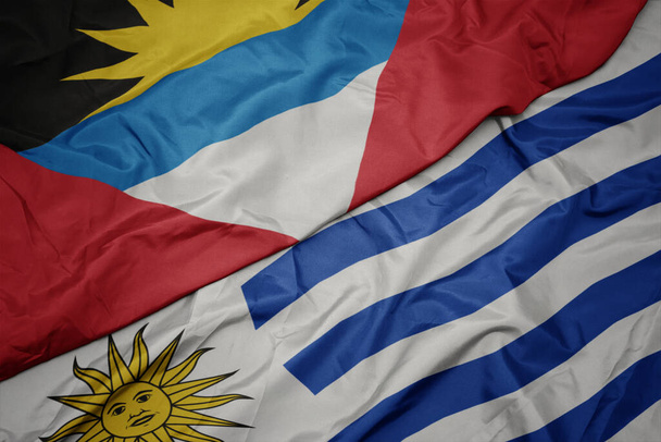 acenando bandeira colorida de uruguai e bandeira nacional de antigua e barbuda. macro
 - Foto, Imagem