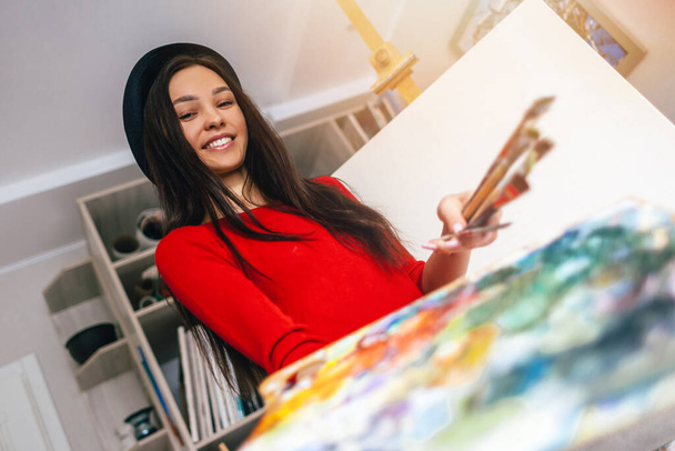 artiste fille dans une robe rouge tient une palette avec des peintures dans le studio pour la peinture
 - Photo, image