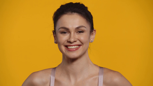 Beautiful woman smiling at camera isolated on yellow - Materiaali, video