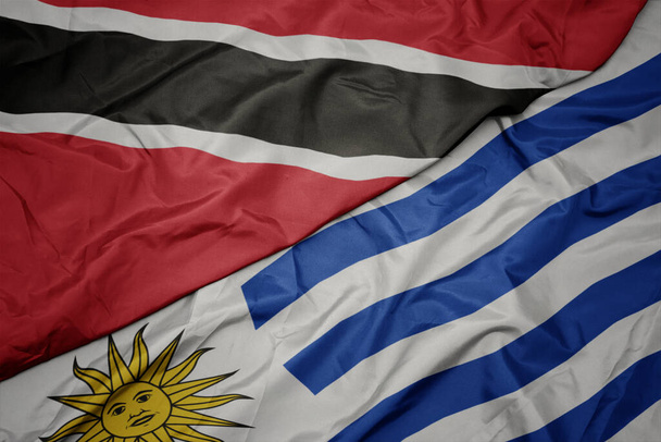 ondeando colorida bandera de uruguay y bandera nacional de trinidad y tobago. macro
 - Foto, Imagen