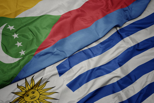 vlající barevnou vlajkou uruguaye a státní vlajkou Komor. makro - Fotografie, Obrázek