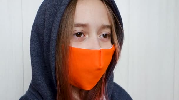 Підліток носить маску обличчя кашляючи. Коронавірус і епідемія грипу. Дівчинка, що стоїть у масці, моргає і озирається навколо.. - Кадри, відео